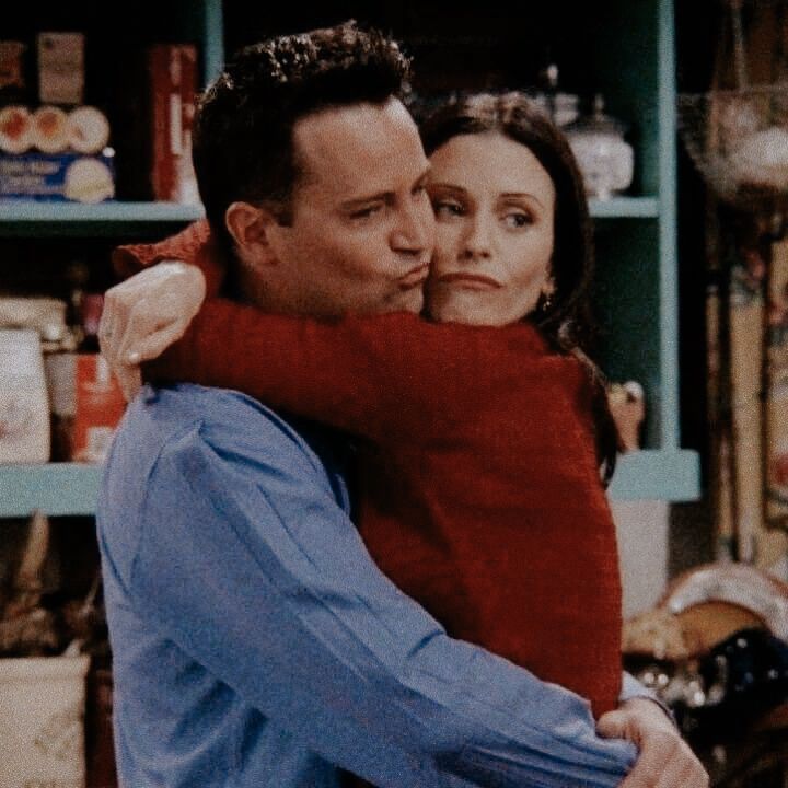 the young man and woman are hugging each other in front of shelves full of items