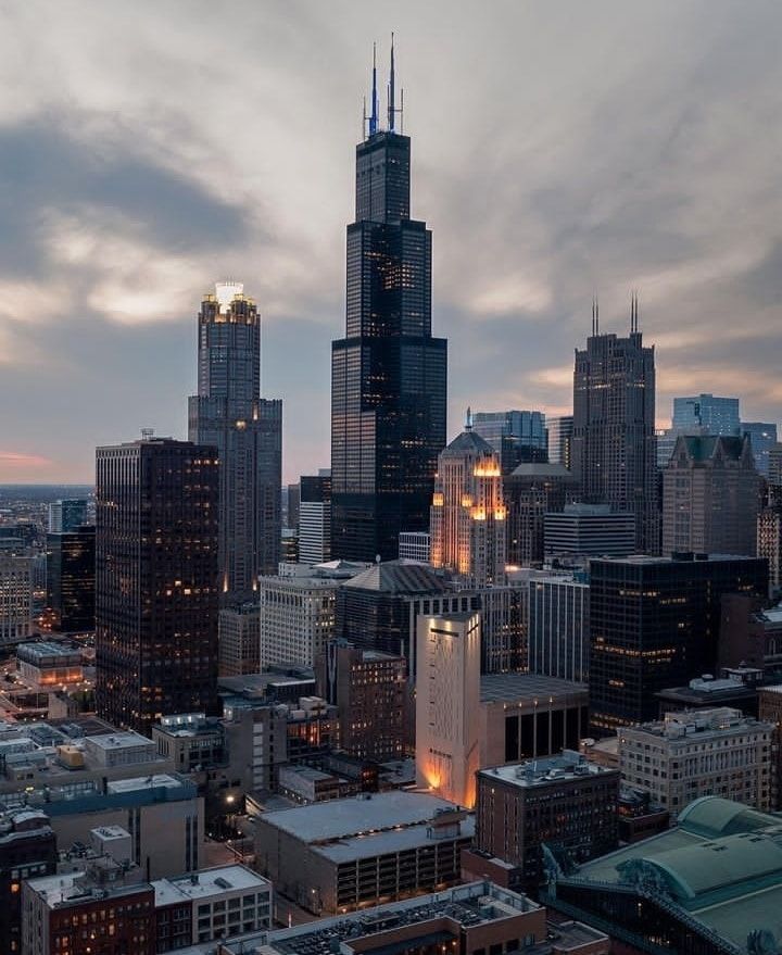 the city skyline is lit up at night, with skyscrapers in the foreground