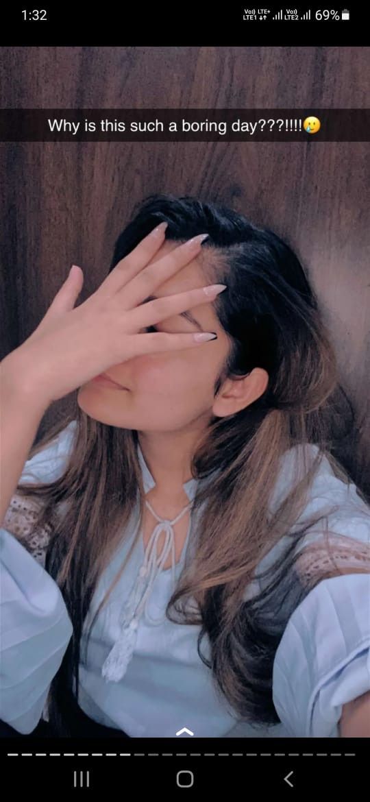 a woman covering her eyes with both hands while sitting in a chair next to a wooden wall