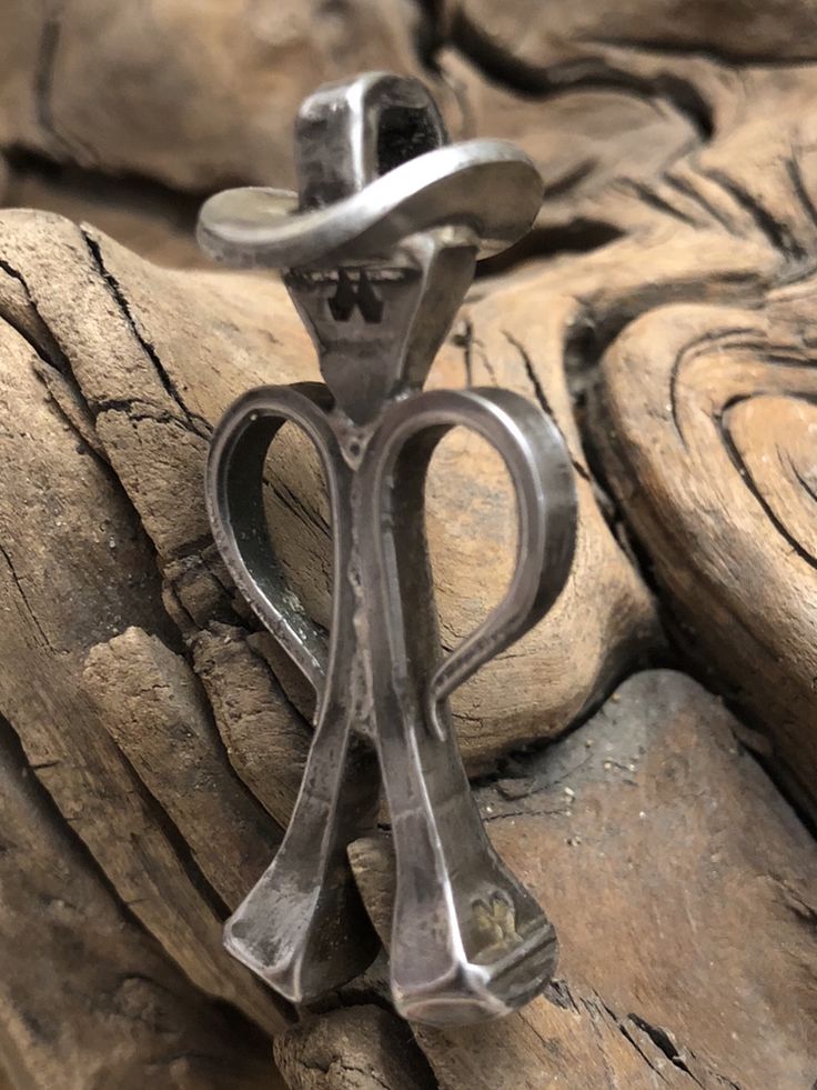 a pair of scissors sitting on top of a piece of wood next to some rocks