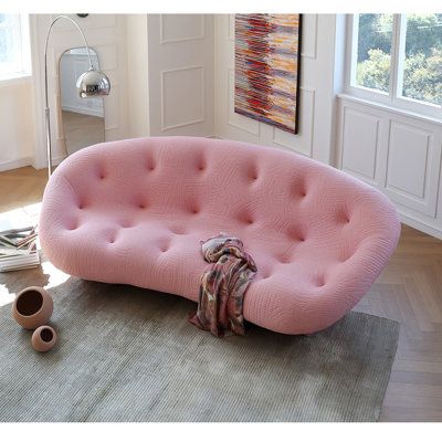 a pink couch sitting on top of a rug in a living room next to a window