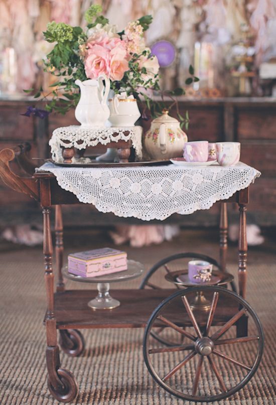 a table topped with flowers and vases on top of a wooden cart filled with books