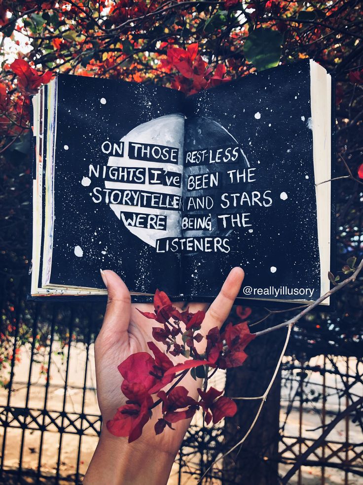 a person holding up a book with an image of the moon and stars on it