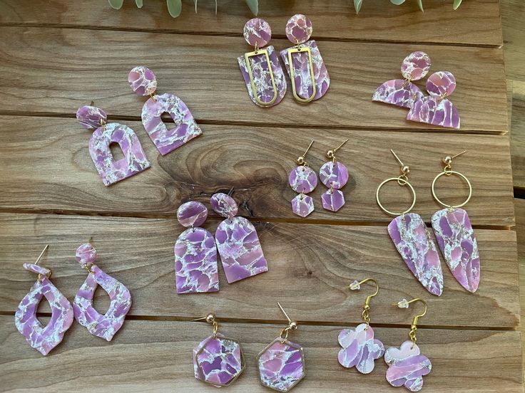 several pieces of pink and white marbled jewelry laid out on a wooden table next to plants