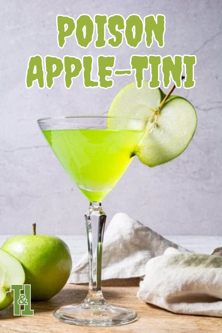 a green drink in a martini glass with an apple on the rim next to it