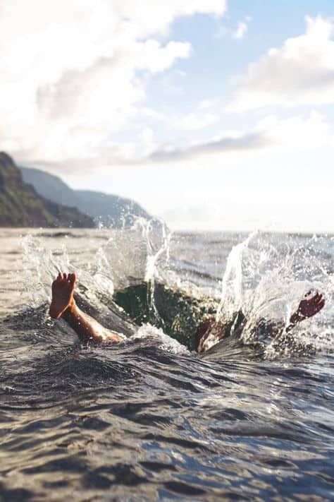 someone is swimming in the ocean with their feet out and one hand on the water's surface