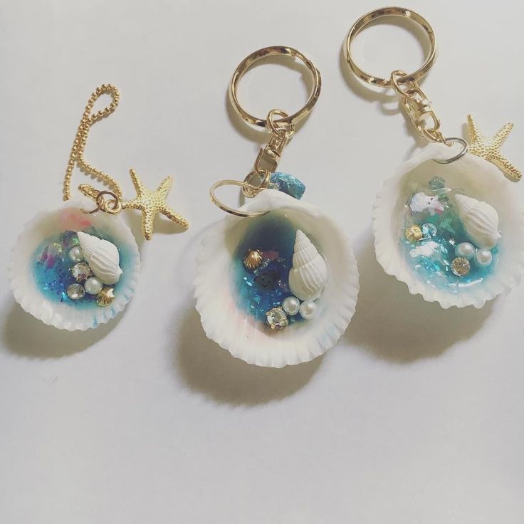 three seashell key chains with charms attached to them