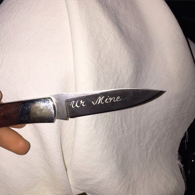 a person holding a knife with the word we more on it's blade in their left hand