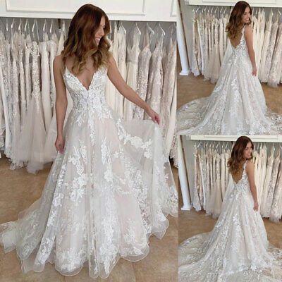 a woman in a white wedding dress standing next to a rack of dresses