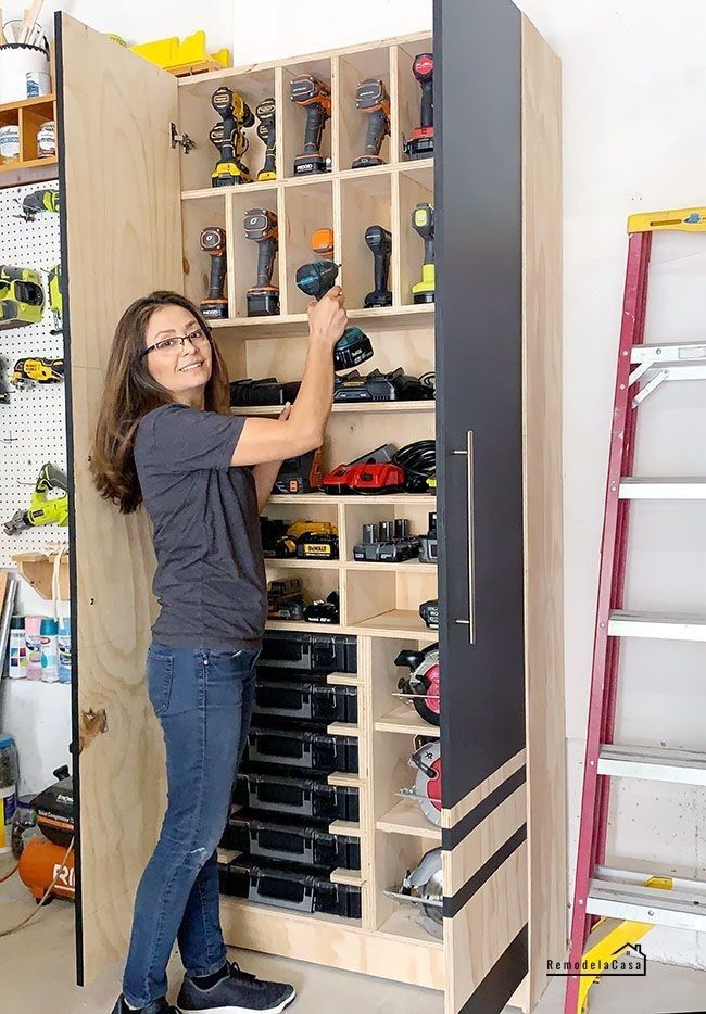 a woman standing in front of a cabinet filled with tools