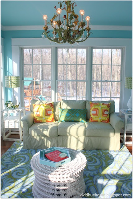 a living room filled with furniture and a chandelier hanging from the ceiling in front of a window