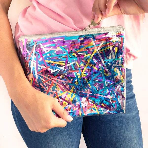 a woman is holding a colorful purse with sprinkles all over her body