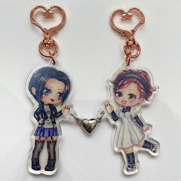 two key chains that have pictures of people on them, one is holding the other's hand