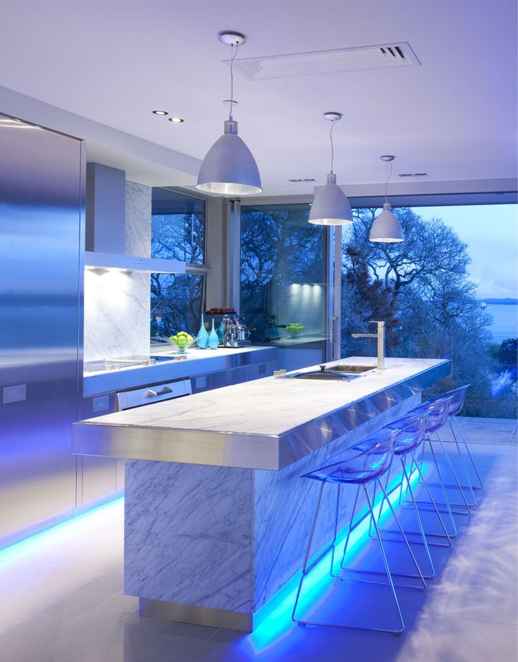 a modern kitchen with an island counter and bar stools in front of the window