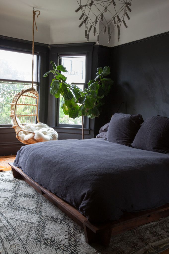 a bedroom with black walls and a hanging chair