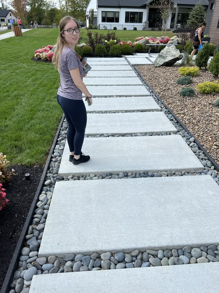 a woman standing on a walkway in front of a house