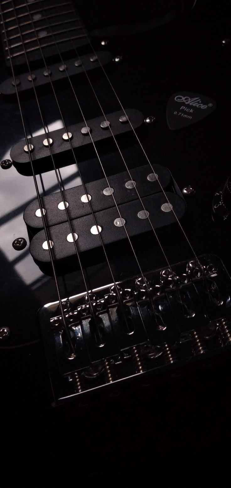 an electric guitar in the dark with its neck and frets showing, close up