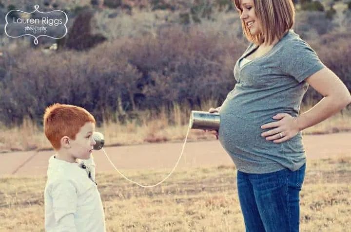 a pregnant woman standing next to a little boy