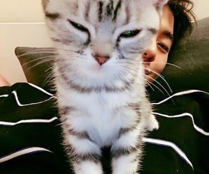 a woman laying in bed with a cat on her chest and eyes wide open to the camera