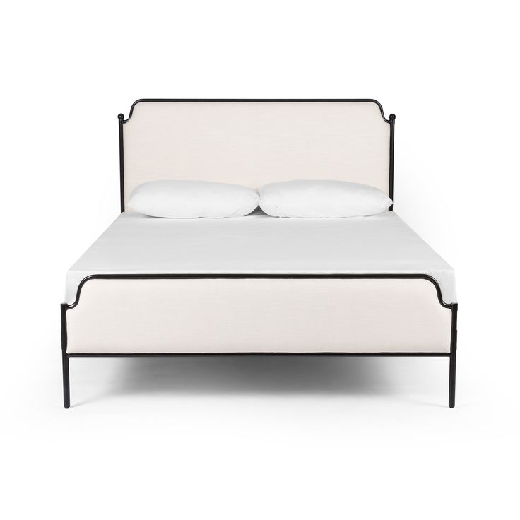 a white bed with two pillows on top of it and a black frame around the headboard