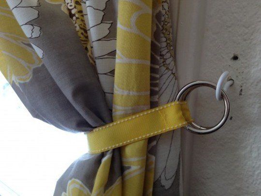 yellow and grey curtains are hanging on the side of a door with a metal hook