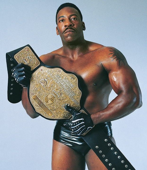 a man in leather shorts holding a wrestling belt