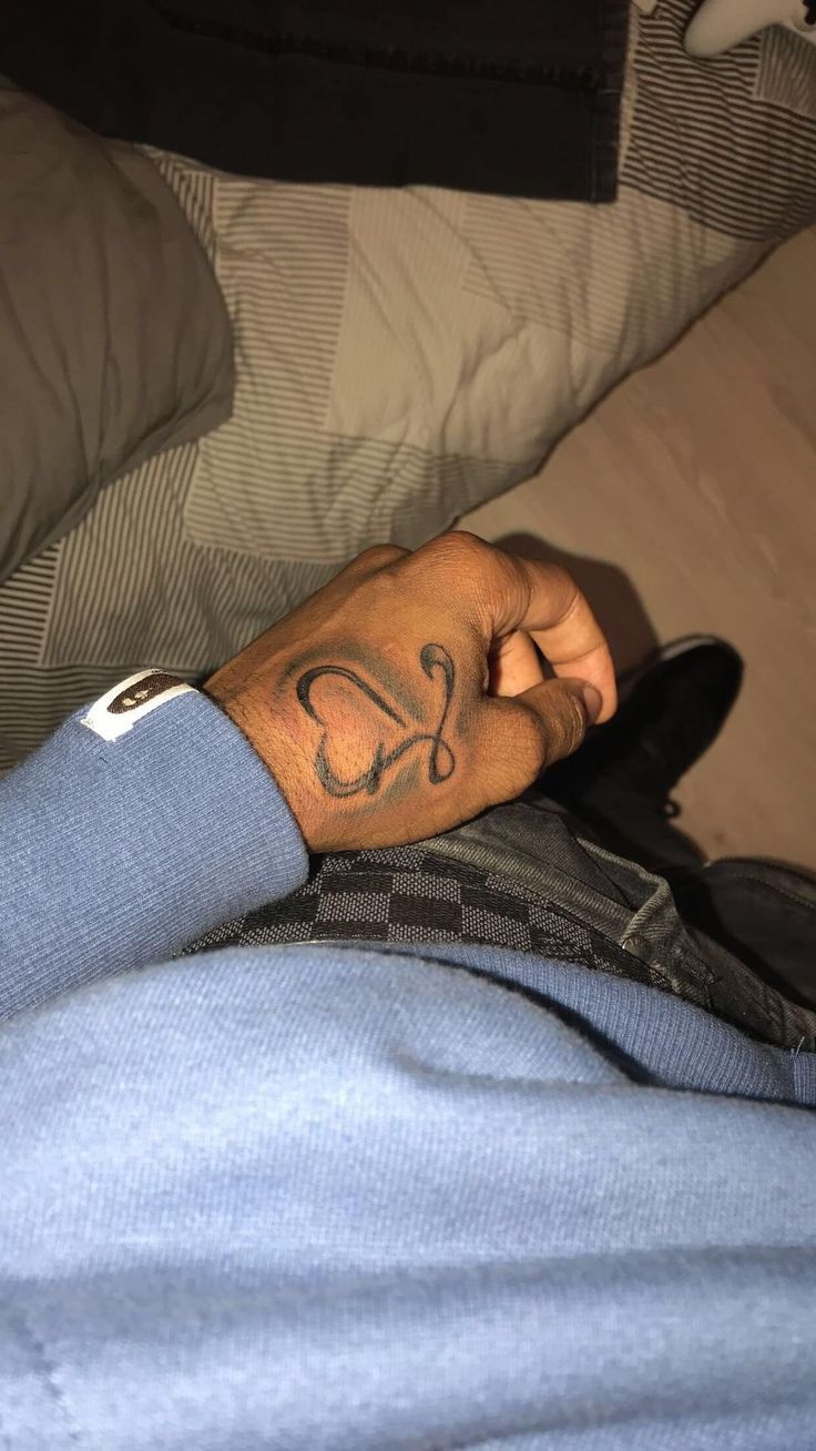 a man with a tattoo on his left hand is laying down and looking at the camera