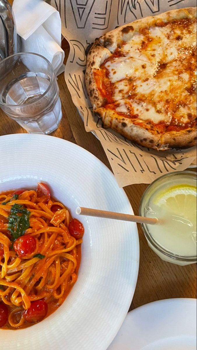 a plate of spaghetti with tomato sauce and a pizza