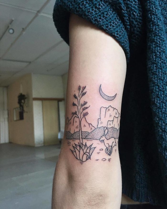 a person with a small tattoo on their arm that has plants growing out of it