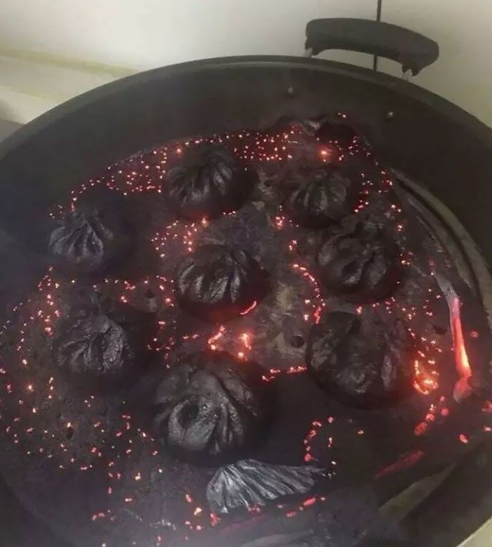 some food is cooking in a black pan on the stove top with red light coming from it