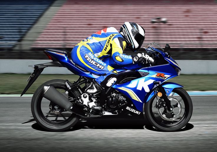 a man riding on the back of a blue motorcycle down a race track in front of a bleachers