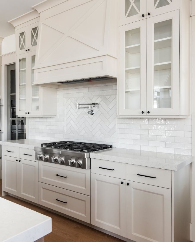 a kitchen with white cabinets and marble counter tops, along with stainless steel oven hoods