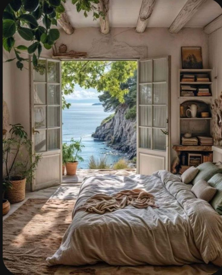 a bedroom with an open door leading to the ocean and trees in front of it