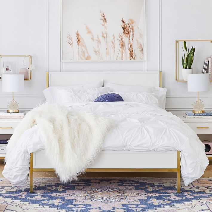 a white bed with fluffy blankets and pillows