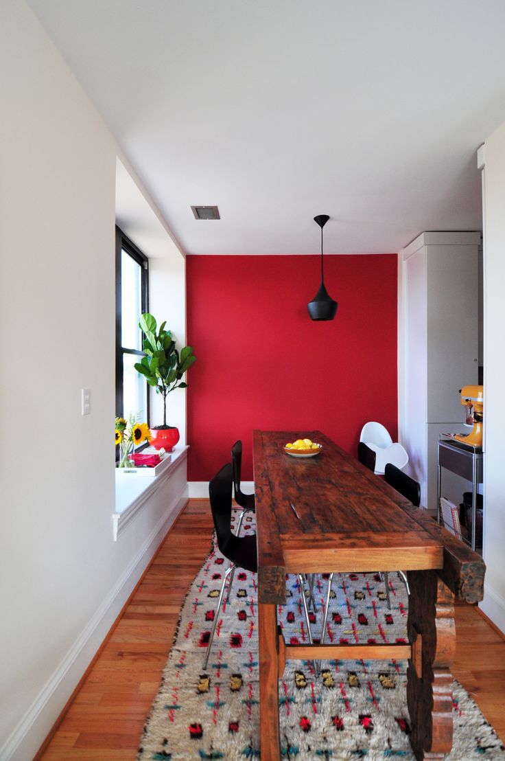 a dining room with red walls and wooden floors