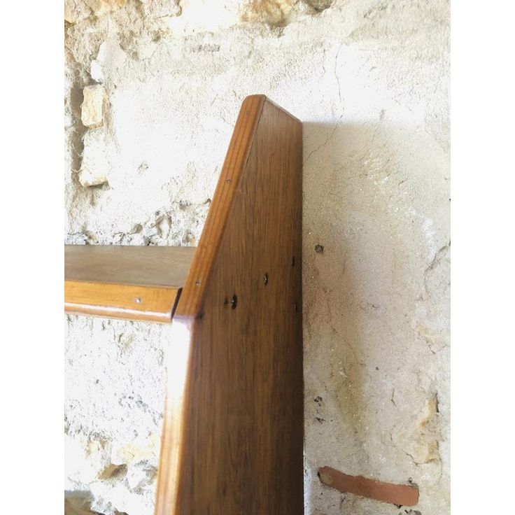 a wooden shelf sitting next to a white brick wall