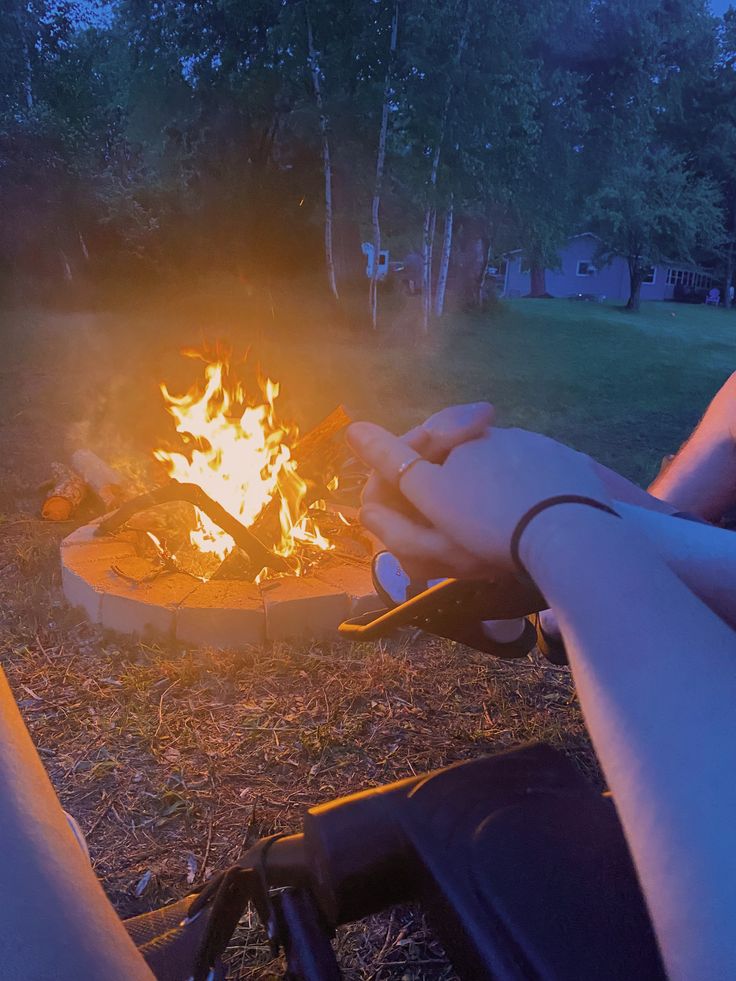 two people holding hands over a fire pit