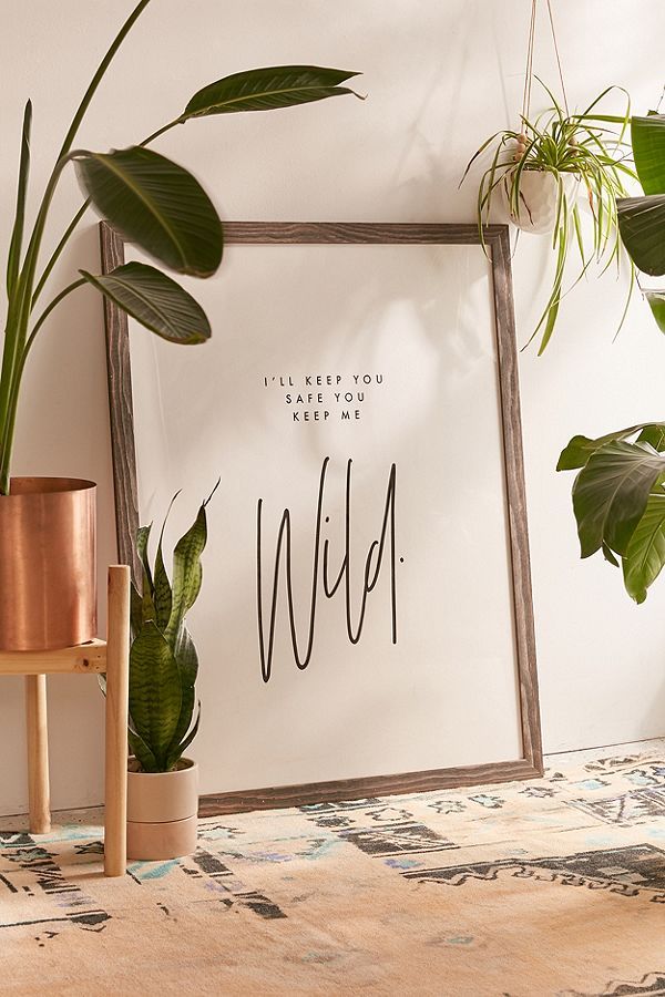 some plants are sitting on a table next to a framed poster