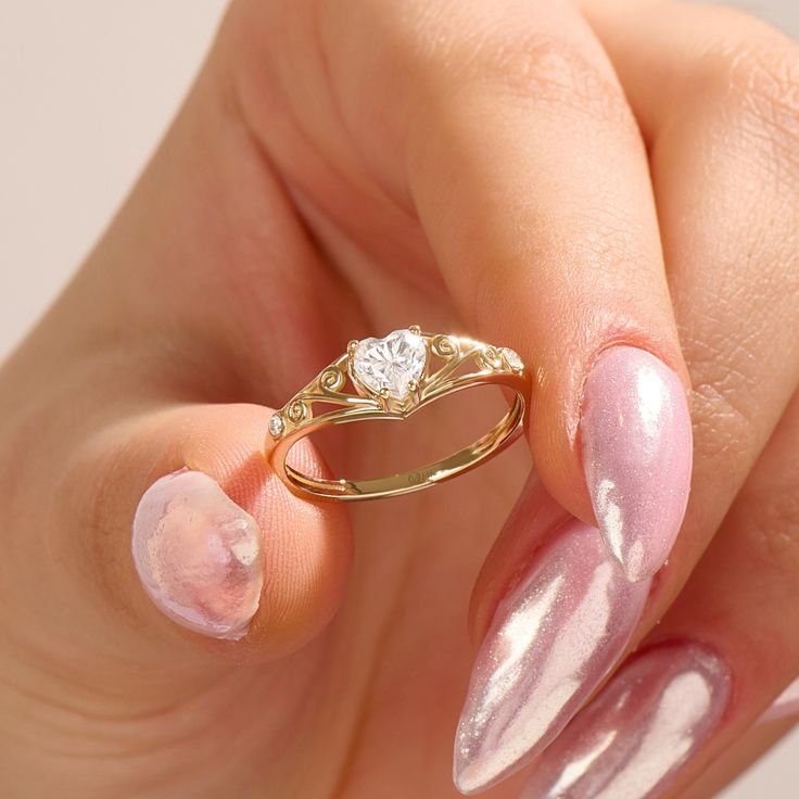 a woman's hand with pink and white manicured nails holding a gold ring