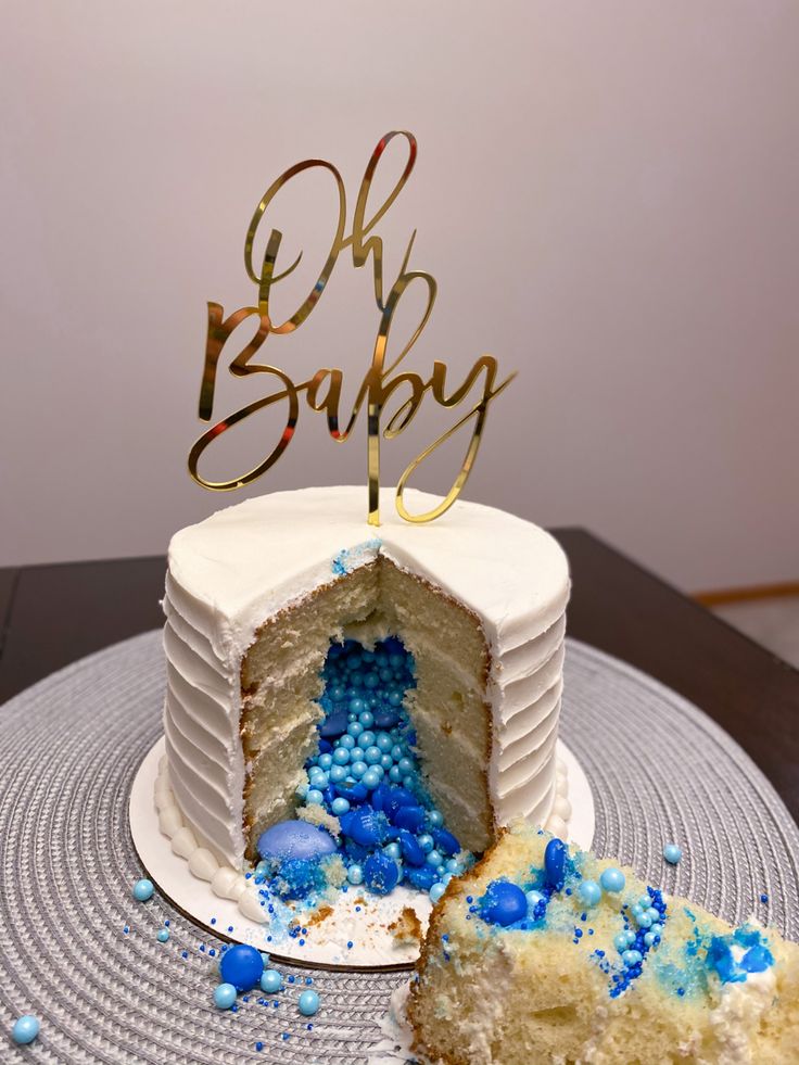 a white cake with blue sprinkles and a gold baby sign on top