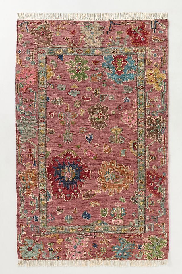 an old rug with many different colors and designs on the front, including pinks, blue