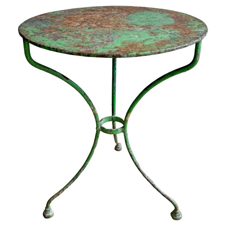 an iron table with green pattered paint on it's top and metal legs