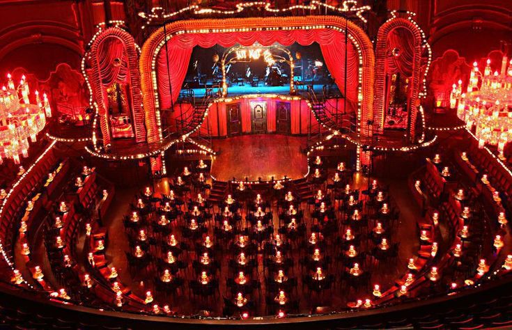 an auditorium filled with lots of lights and chandeliers on the stage in front of it