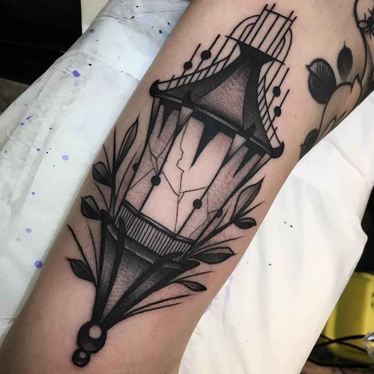 a black and white photo of a birdcage tattoo on the arm