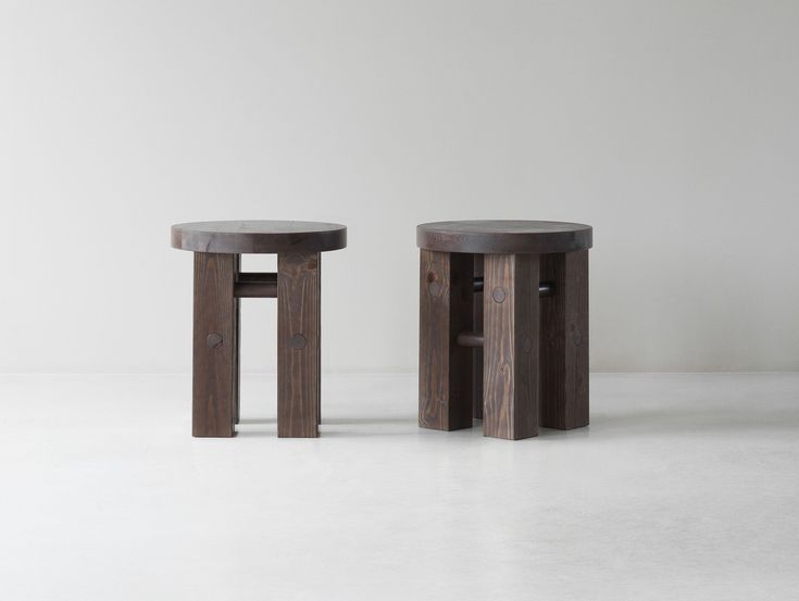 two wooden stools sitting next to each other on a white floor in front of a wall