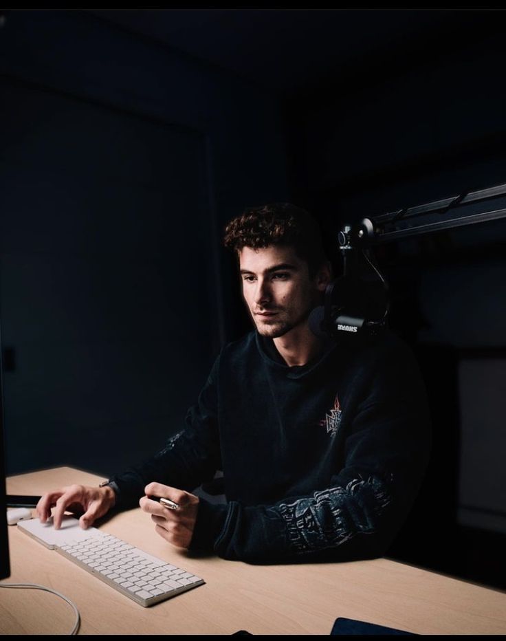 a man sitting at a desk with a computer in front of him and headphones on