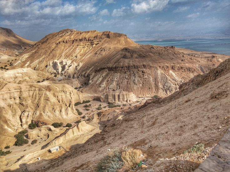 the mountains are covered in brown and white sand, under a blue sky with clouds