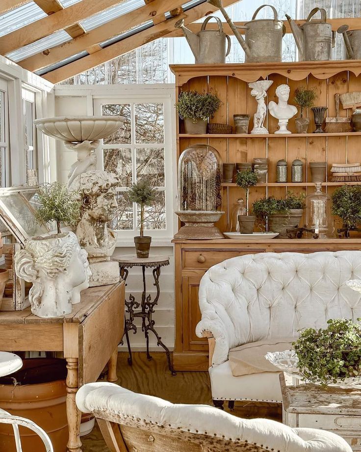 a living room filled with furniture and lots of plants on top of wooden shelves next to windows