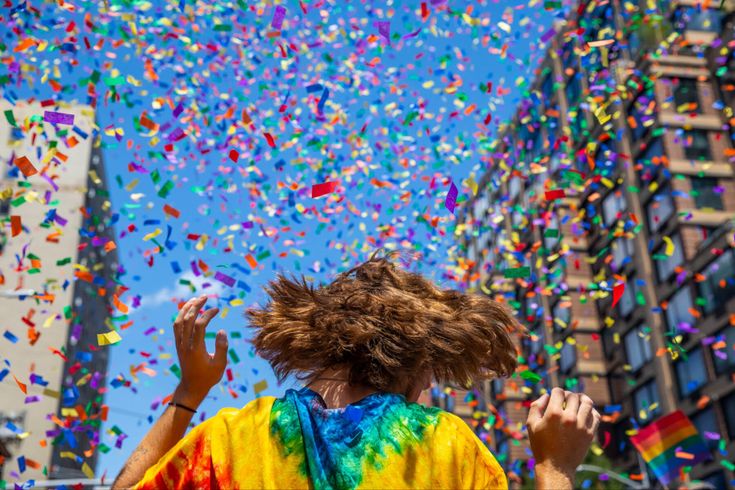 a man in a tie - dyed shirt is surrounded by confetti and streamers