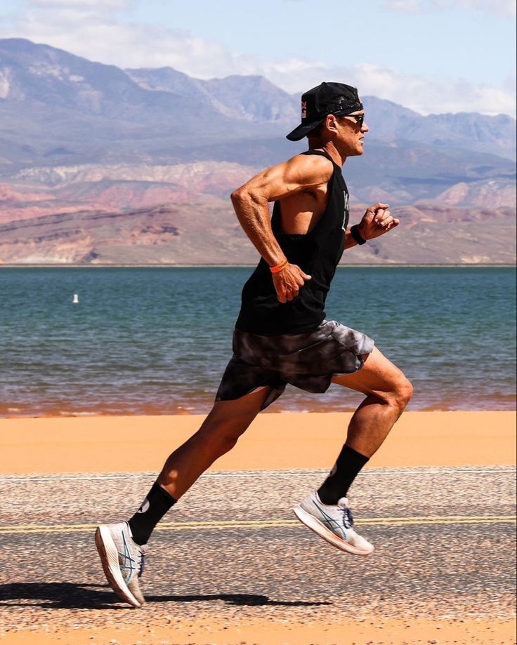 a man running on the beach with mountains in the background